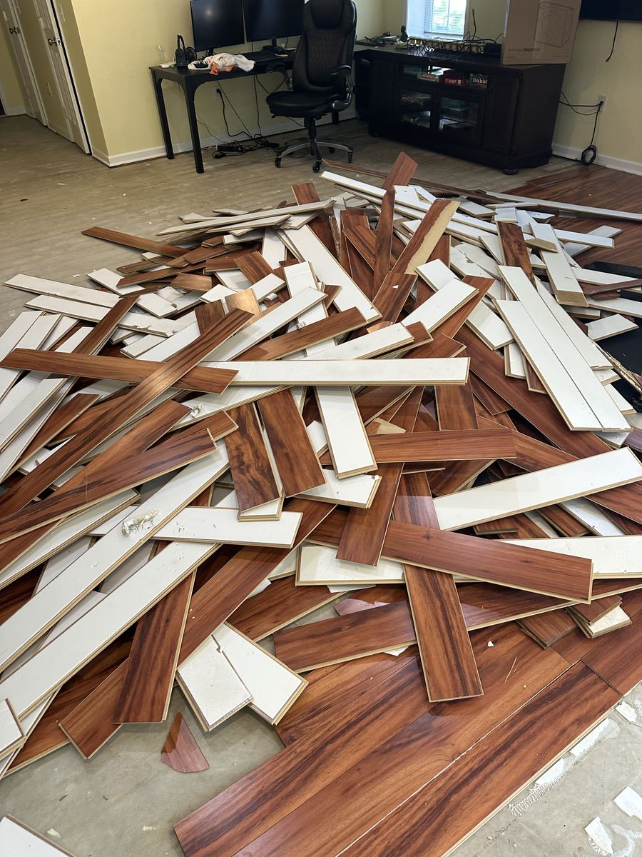 Pile of removed laminate flooring and baseboard — basement renovation
