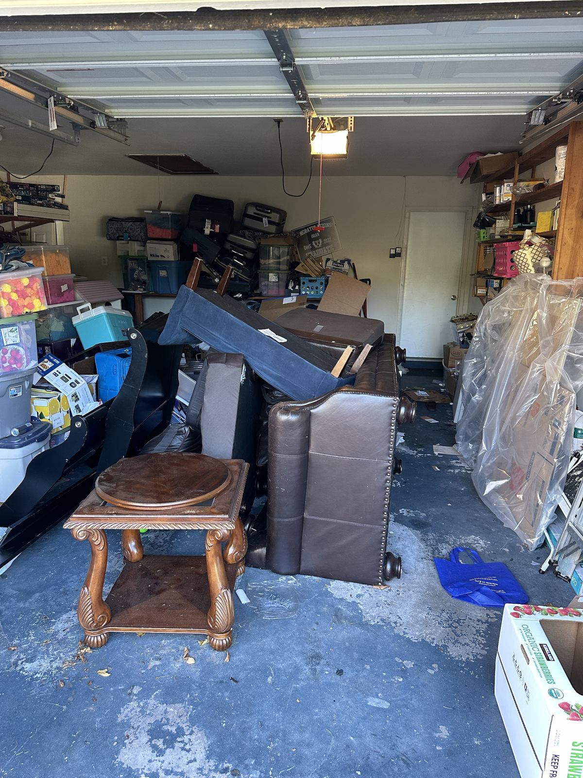 Garage packed with furniture, luggage, and storage bins before cleanout — Leesburg, VA