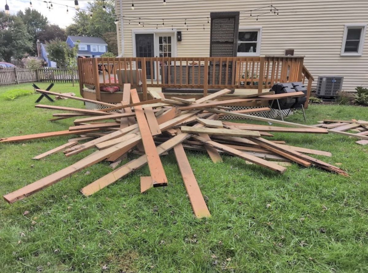 Old deck boards piled on a backyard lawn after a deck replacement — Floris, Herndon VA